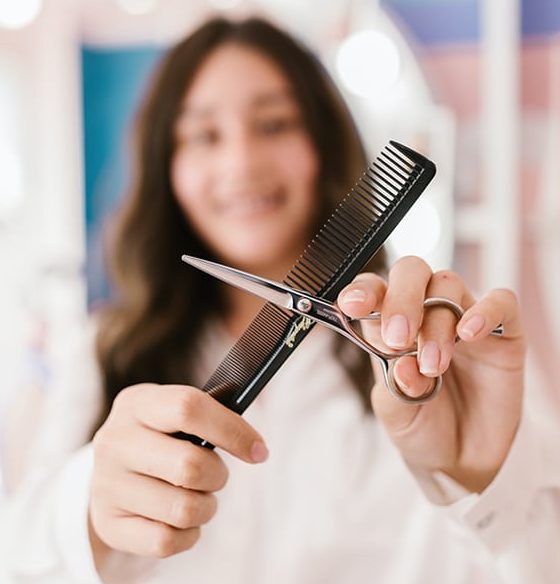 A person holding scissors and a comb