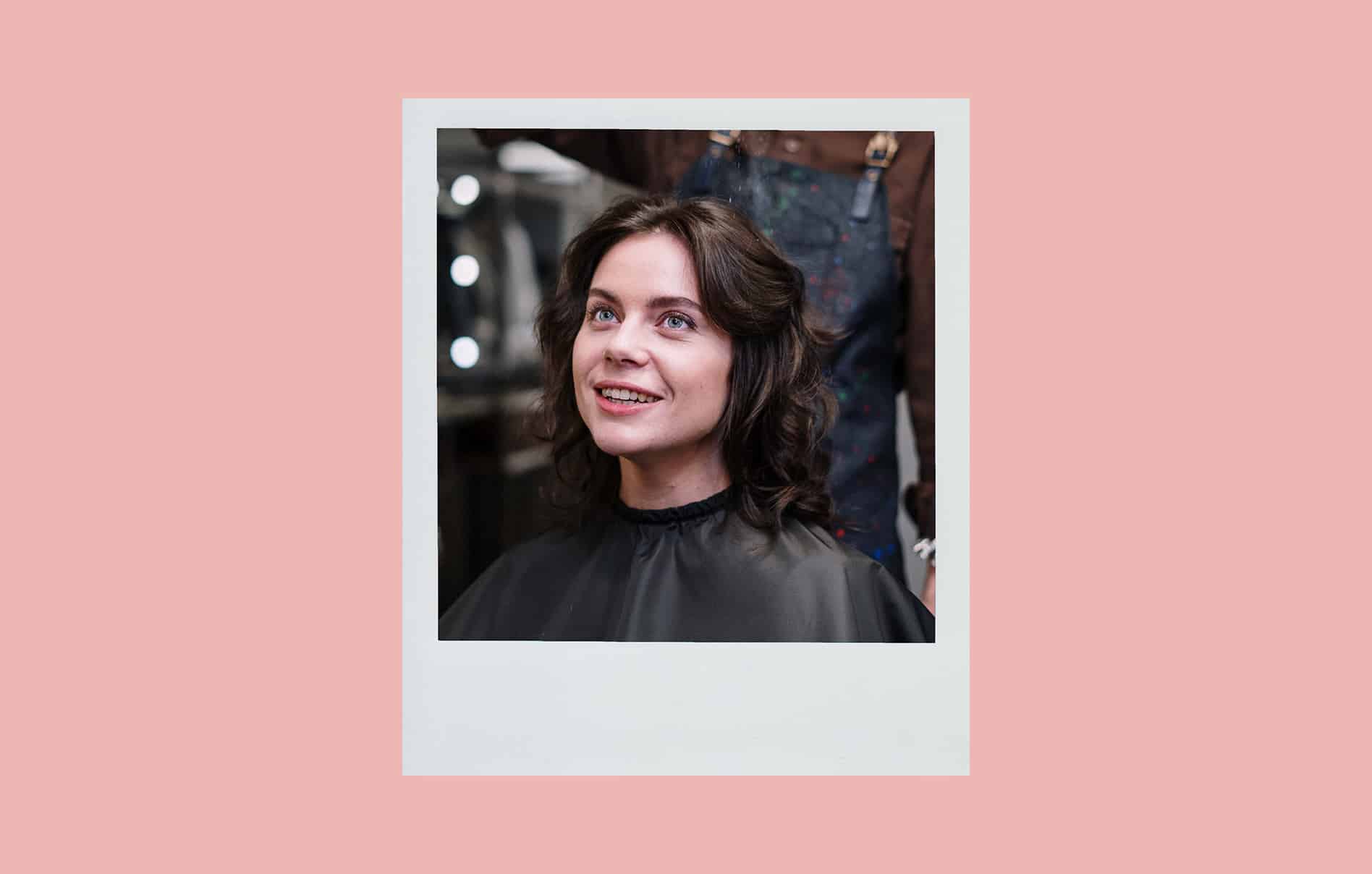 Polaroid of a person smiling with freshly styled hair in a salon