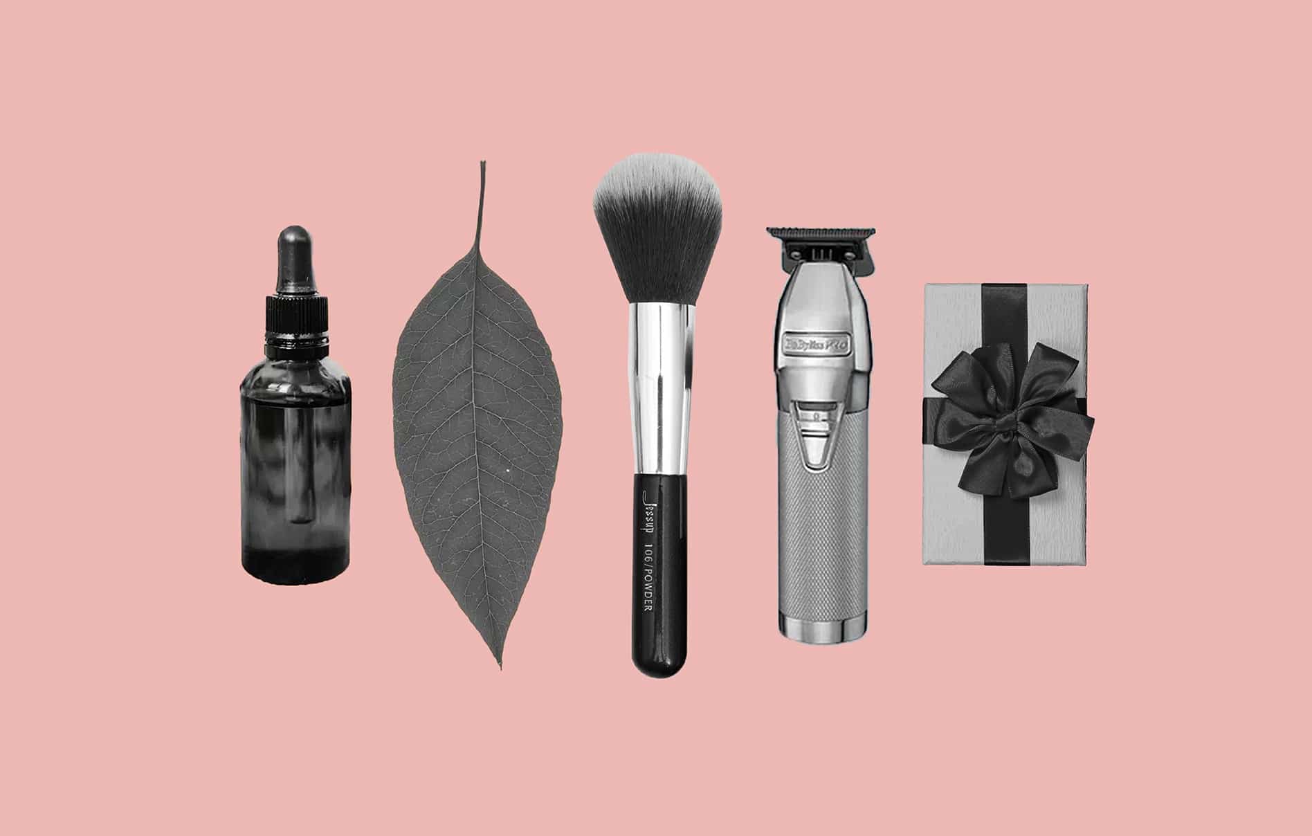A bottle of face oil, a leaf, a makeup brush, clippers, and a small wrapped gift
